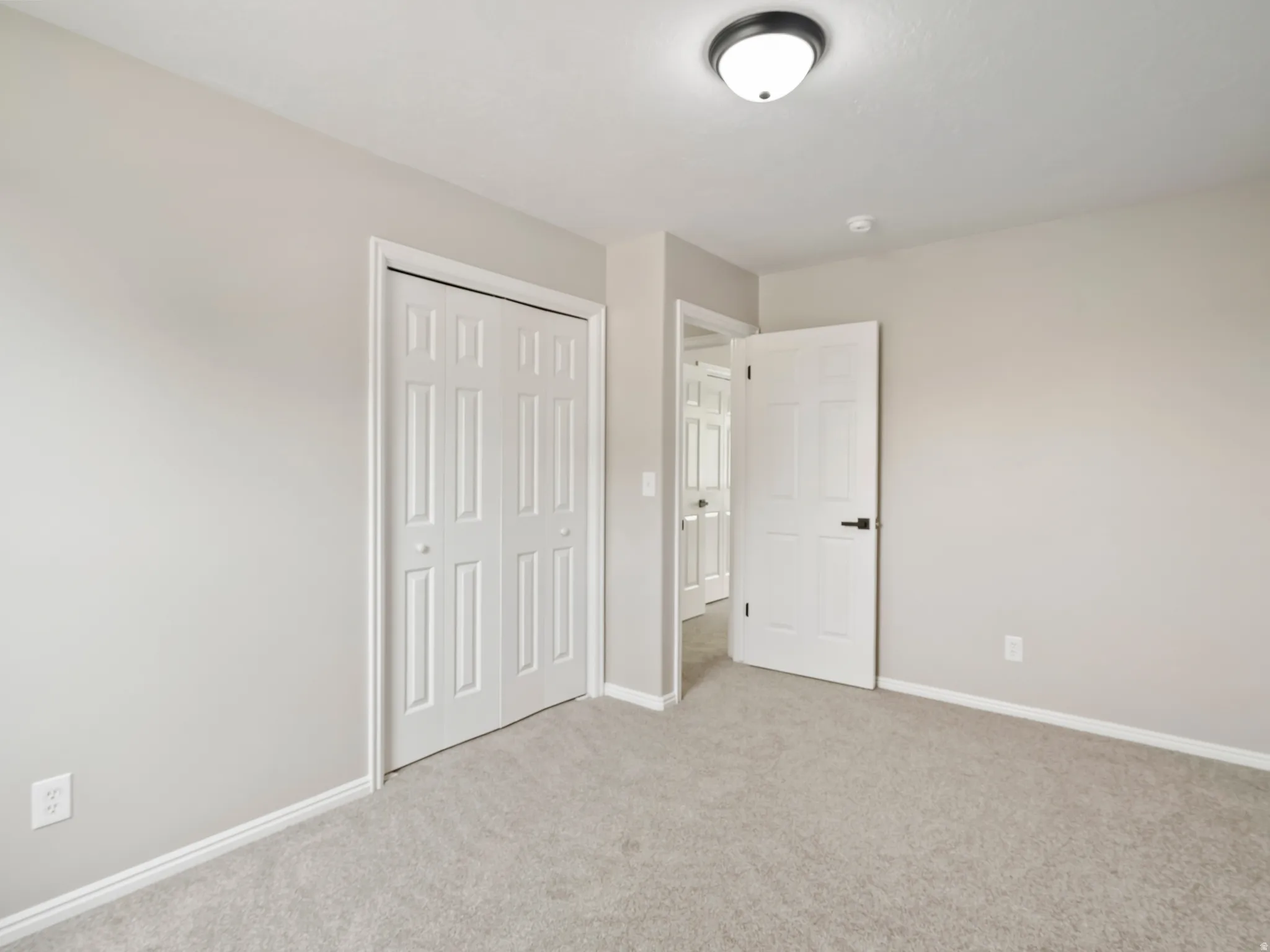 Carpeted room with light gray walls, featuring a bi-fold closet door and white trim