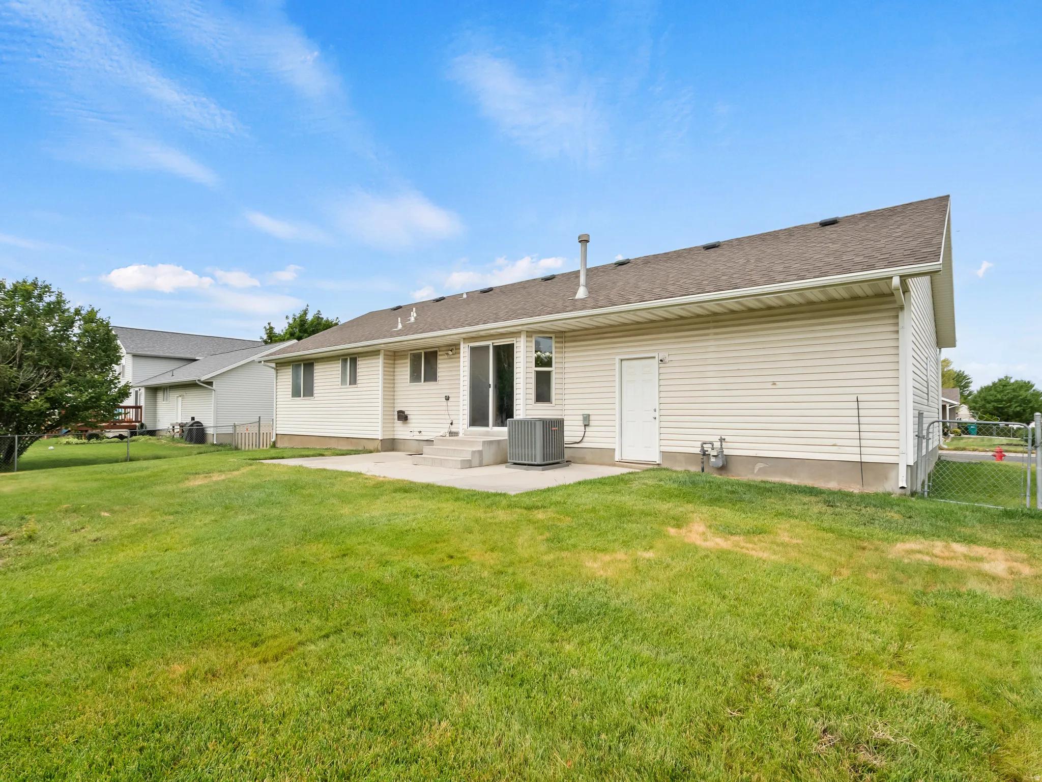 Rear exterior with light-colored siding and a multi-level concrete patio
