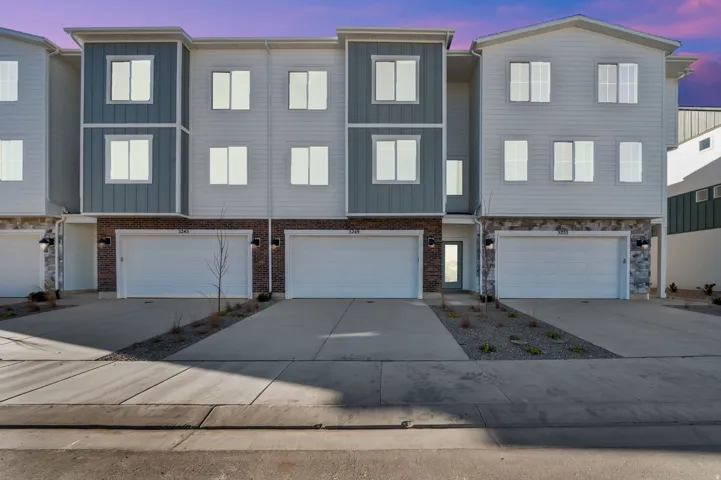 Contemporary multi-level townhome featuring a mixed material facade with horizontal siding, vertical siding, and stone accents