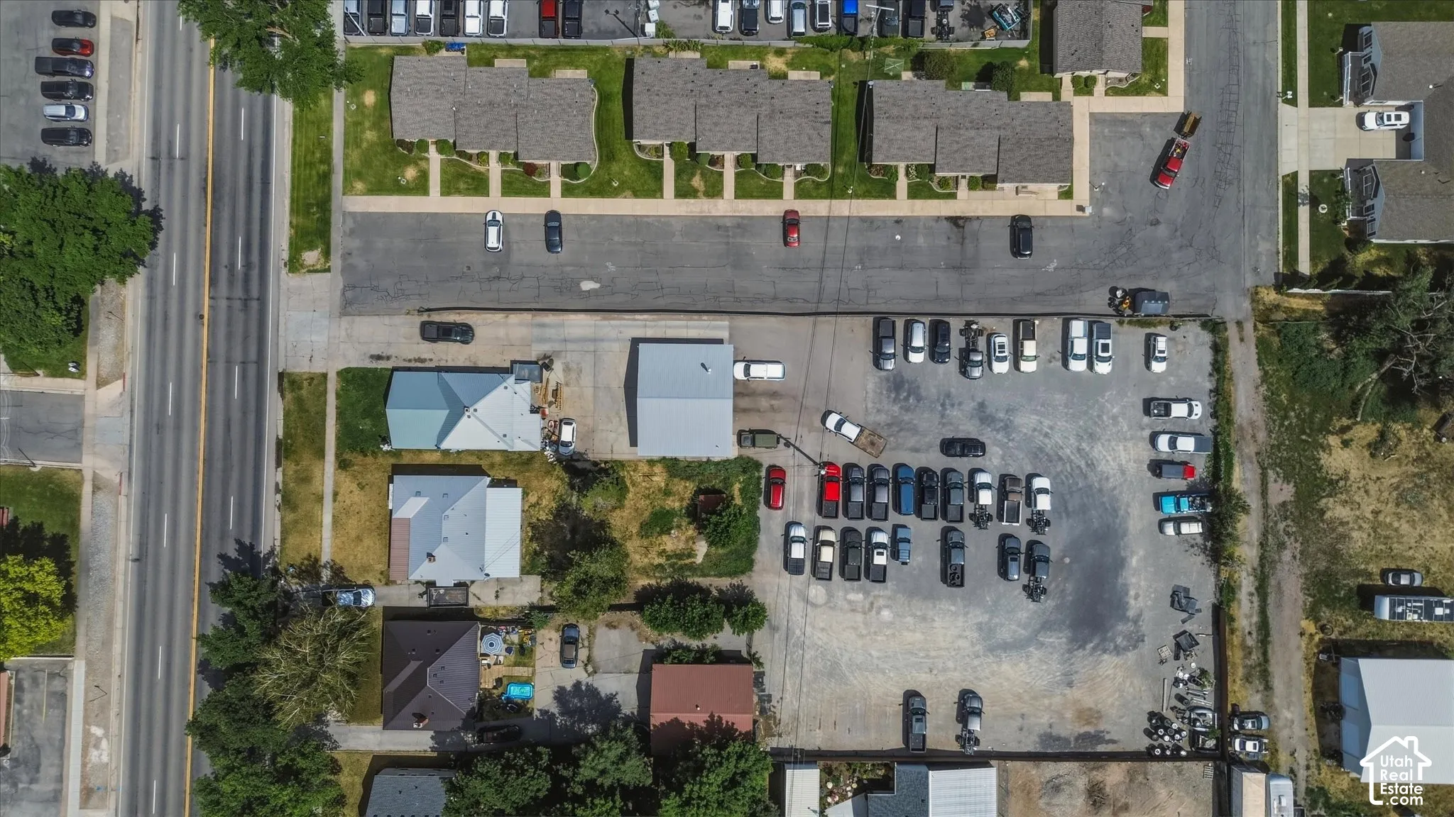 Commercial property featuring a large paved parking area, multiple structures with metal roofs, and direct access to a main thoroughfare