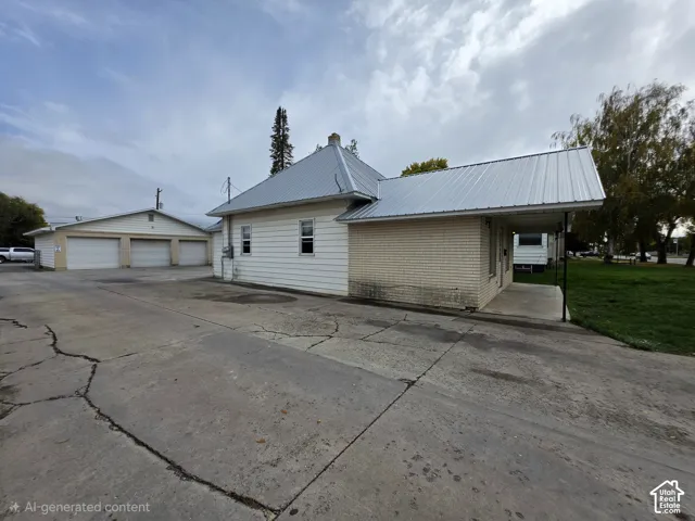 Exterior featuring a metal roof, brick and horizontal siding facade, covered patio, and detached three-car garage