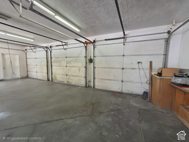Three-car garage featuring concrete flooring, fluorescent overhead lighting, and built-in wood cabinetry