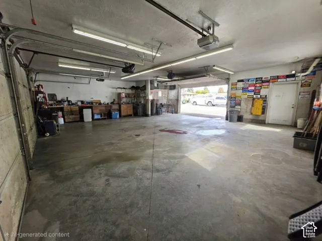 Expansive multi-car garage featuring a concrete floor, built-in wooden workbench, and overhead fluorescent lighting