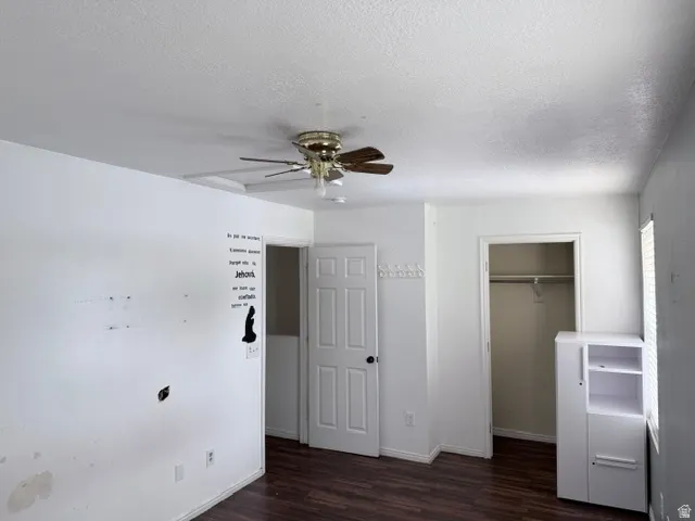 Room featuring wood-finish flooring, white walls, and a ceiling fan