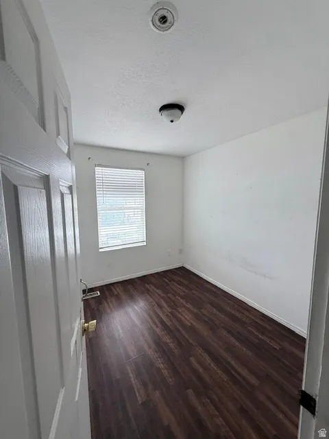 Interior room featuring wood-finish flooring, white walls, and a window with horizontal blinds