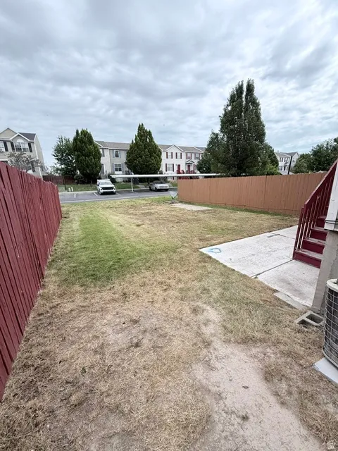 Private fenced yard featuring a concrete patio and red wood fencing