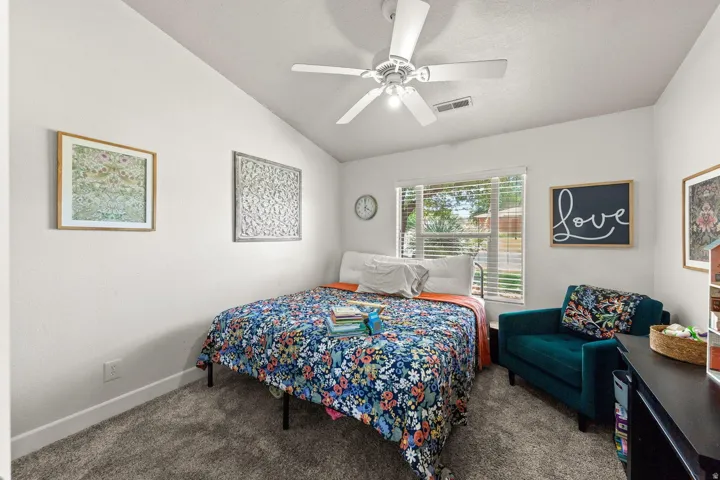 Vaulted ceiling with a ceiling fan, window with horizontal blinds, neutral wall paint, gray carpet flooring, and white baseboards