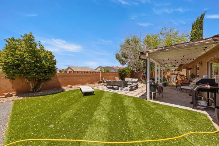 Expansive backyard featuring a combination of artificial turf and paver patio areas