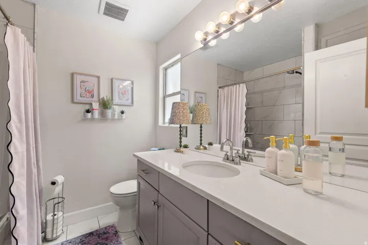 Full vanity mirror with globe light fixture, single sink with chrome faucet, and spacious countertop