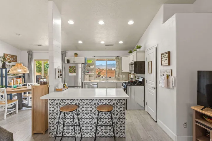 Kitchen featuring a patterned island with countertop seating, white cabinetry, stainless steel appliances, and recessed lighting