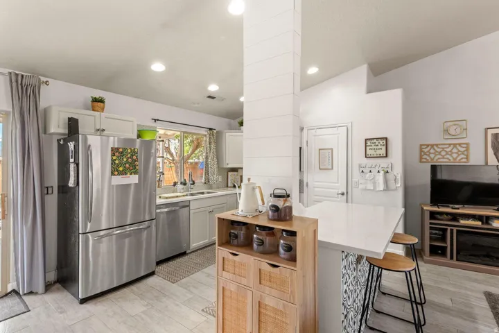 Kitchen featuring stainless steel appliances, light cabinetry, and an eat-at peninsula with a solid surface countertop