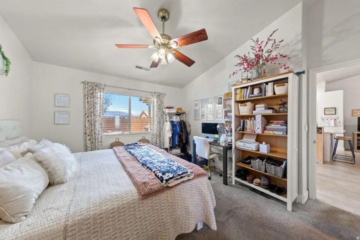 Carpeted bedroom with a vaulted ceiling and a ceiling fan with light fixture