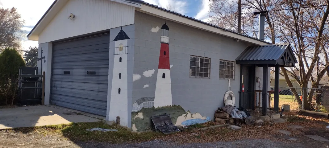 Commercial-style building featuring a wide roll-up door, corrugated metal roofing, and a covered entry porch