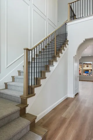 Grand staircase featuring light wood-finish treads and risers with carpeted runners