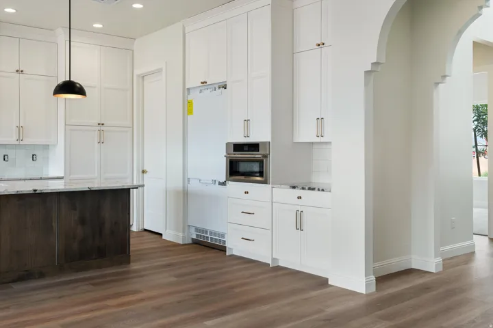 Contemporary kitchen featuring white cabinetry and a dark wood-finish island