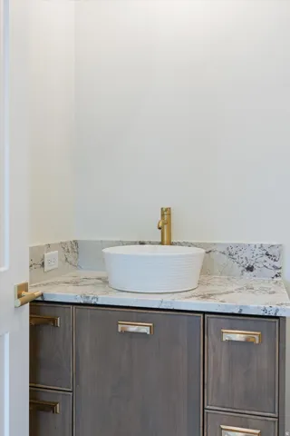 White vessel sink with a gold-finish faucet set against a light-toned countertop