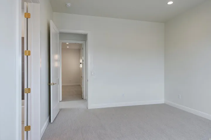 Neutral-toned room featuring light gray carpeting, white walls, and bright white baseboards