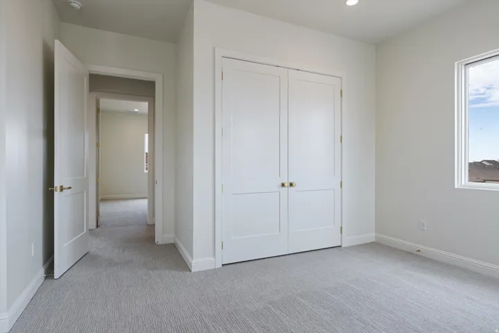 Spacious room featuring light gray patterned carpeting, white trim, and a window with a simple white frame