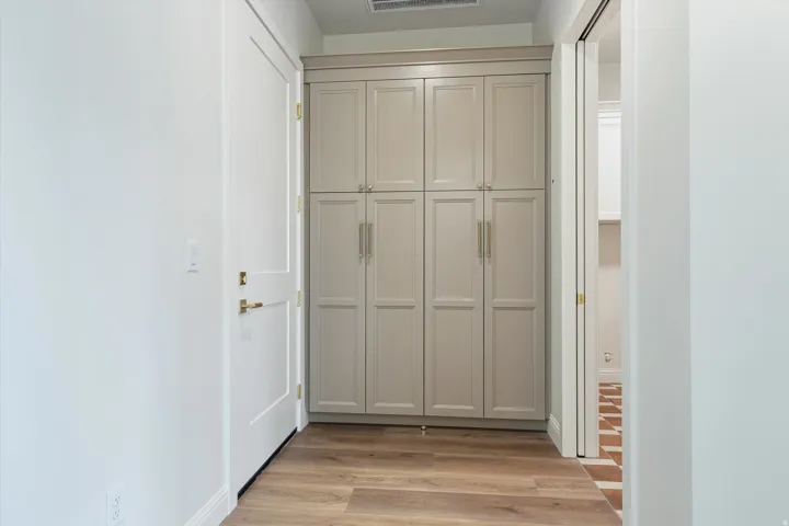 Integrated built-in cabinetry with paneling, brass hardware, and wood-finish flooring