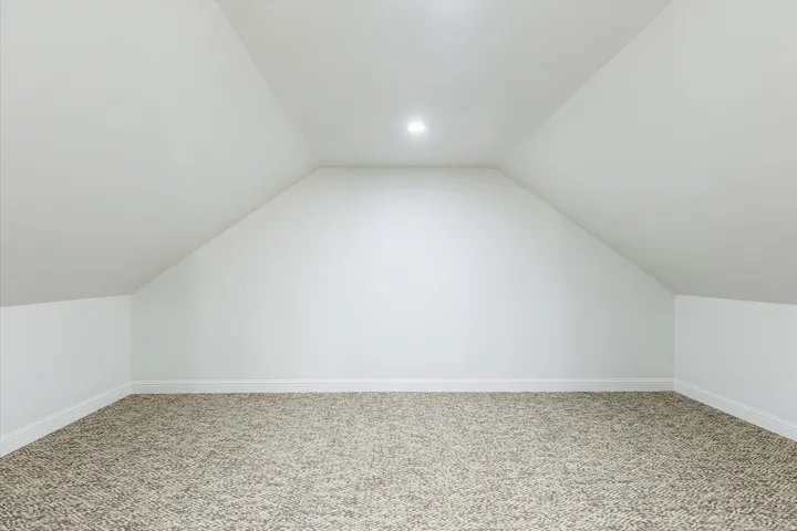 Carpeted room with sloped ceilings and recessed lighting