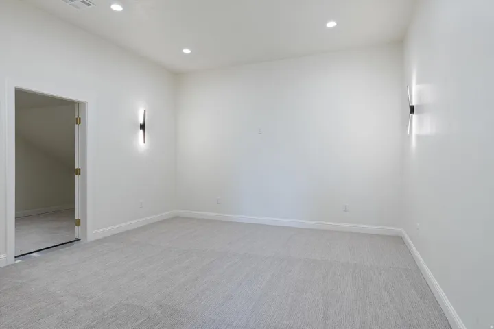 Neutral wall tones with recessed lighting and contemporary wall sconces