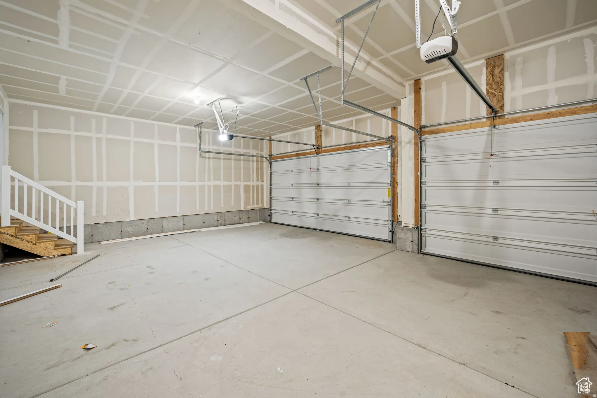 Two-car garage featuring a concrete floor, two white garage doors, and unfinished drywall walls. This is not the actual home being built but a representation of the features available in this home. Colors and finishes may differ from those shown.