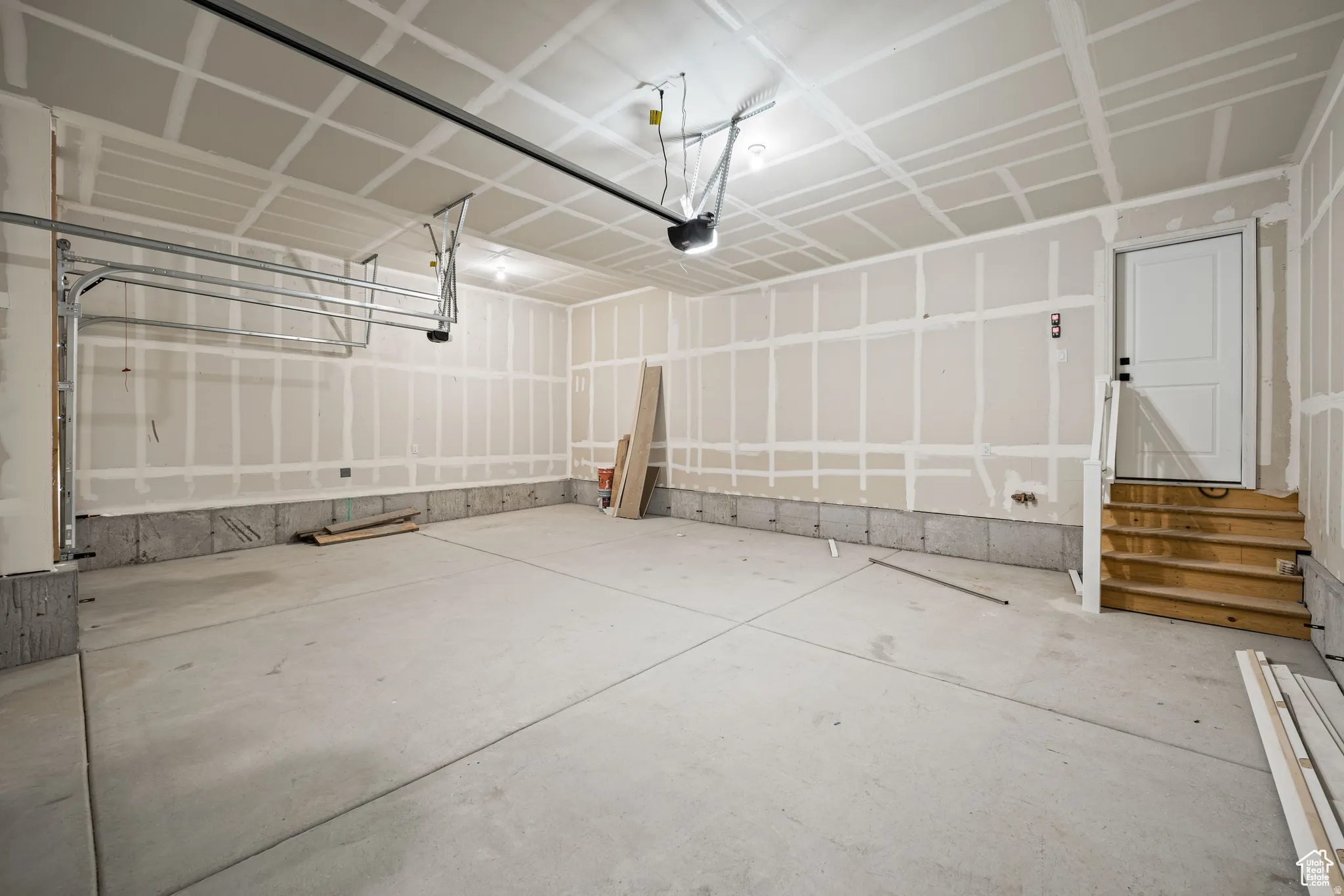 Spacious garage with unfinished drywall, concrete flooring, and an overhead garage door mechanism. This is not the actual home being built but a representation of the features available in this home. Colors and finishes may differ from those shown.
