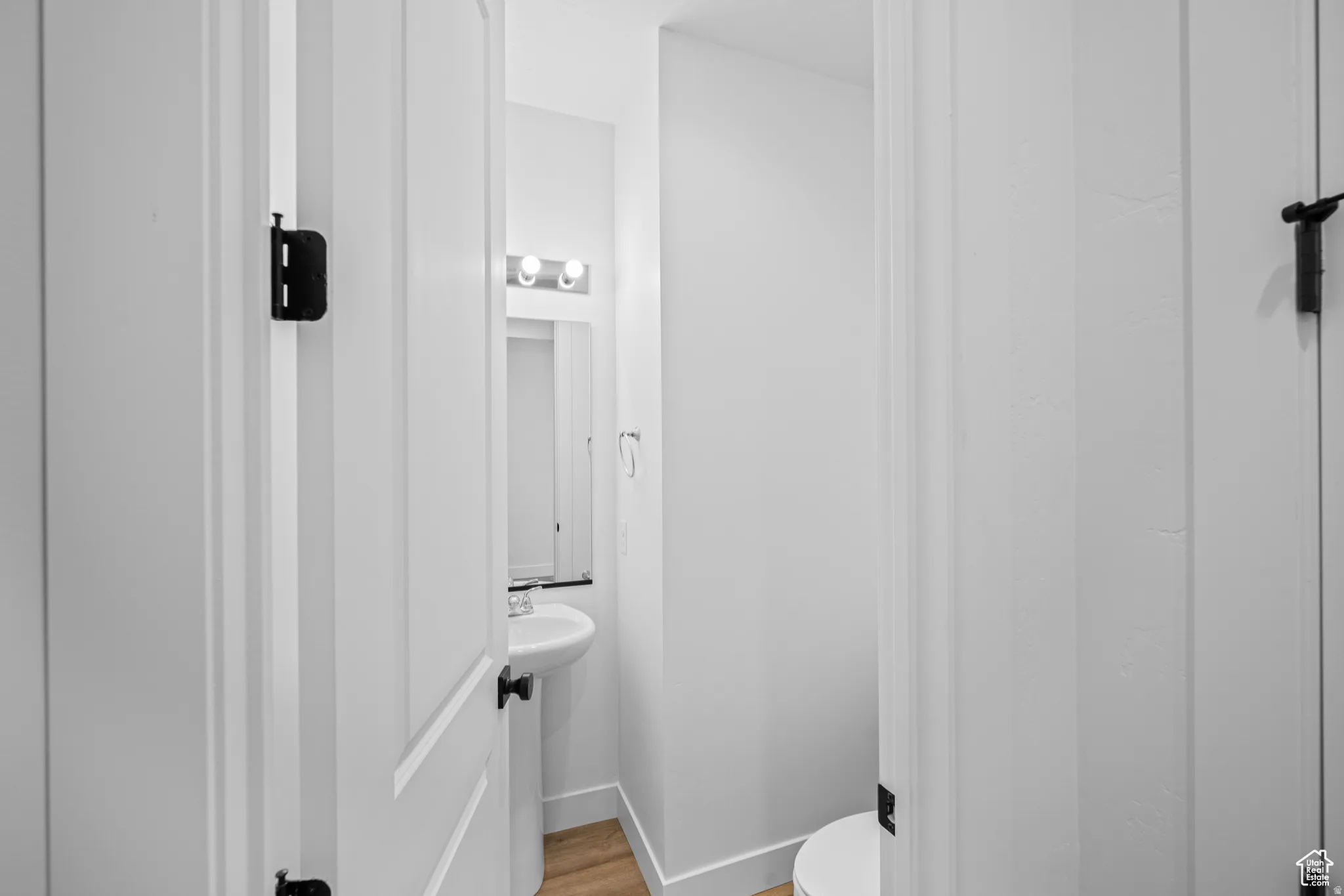Compact powder room featuring a pedestal sink, wall-mounted mirror, and overhead vanity lighting. This is not the actual home being built but a representation of the features available in this home. Colors and finishes may differ from those shown.