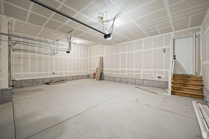 Spacious garage with unfinished drywall, concrete flooring, and an overhead garage door mechanism. This is not the actual home being built but a representation of the features available in this home. Colors and finishes may differ from those shown.