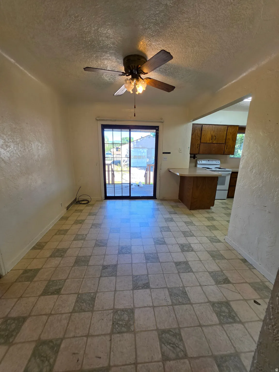 Tiled flooring, ceiling fan with integrated lighting, sliding glass door, and a built-in breakfast bar
