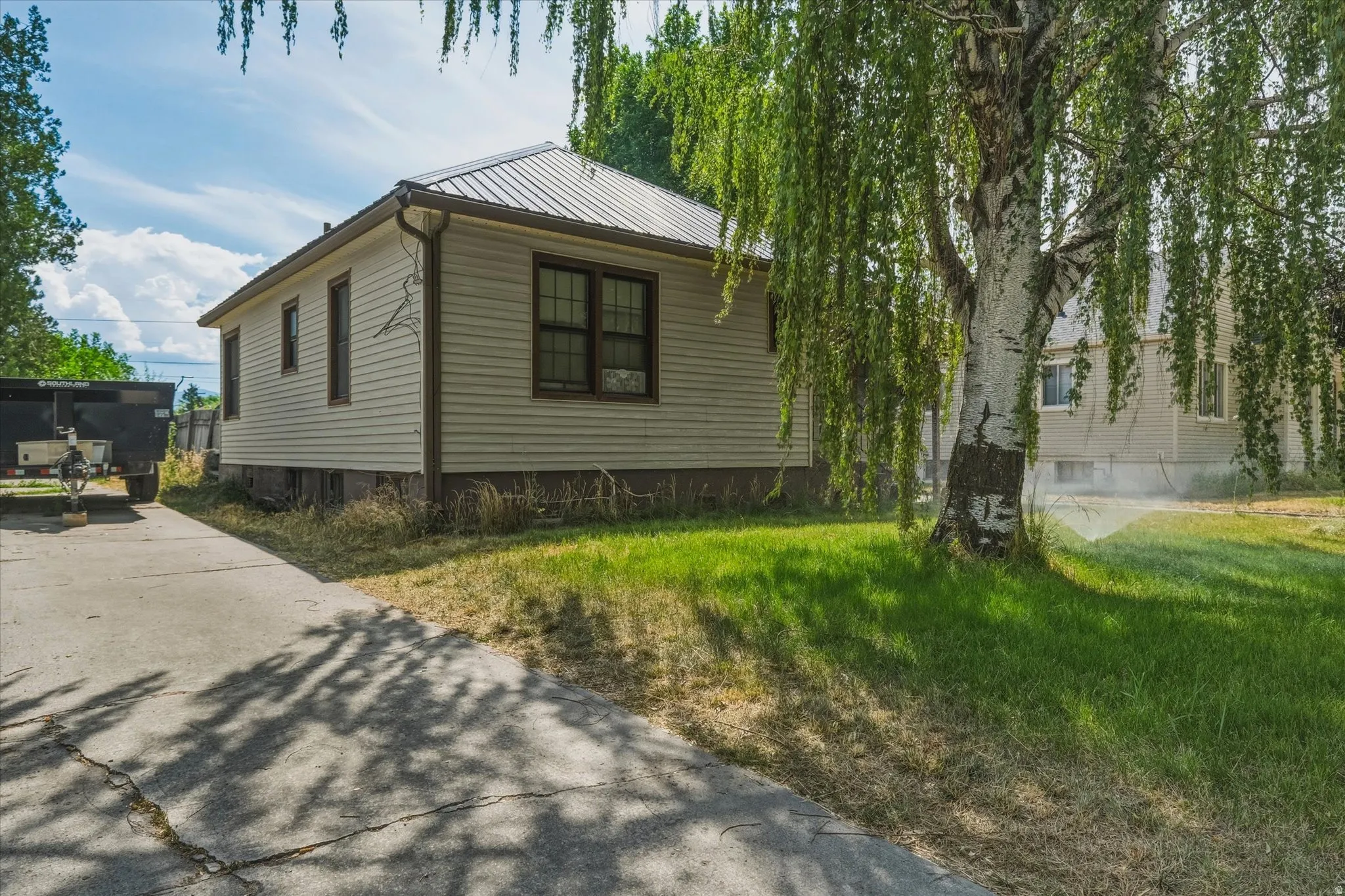 Exterior siding with dark trim windows, metal roof, and concrete driveway
