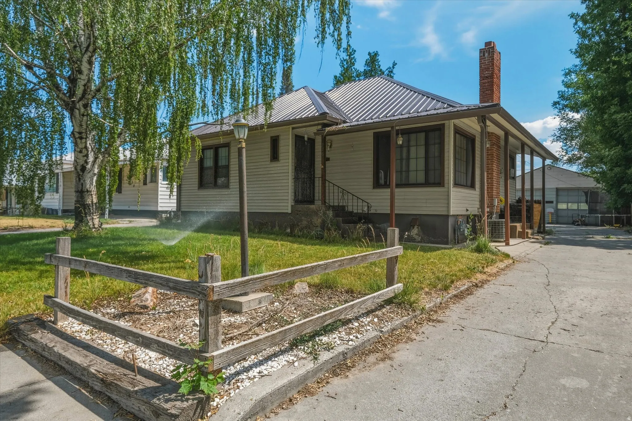 Ranch-style exterior featuring a metal roof, covered porch, and a brick chimney