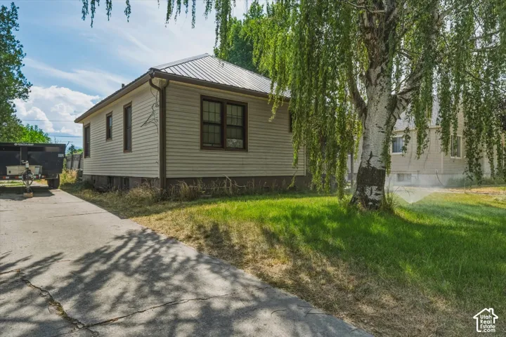 Exterior siding with dark trim windows, metal roof, and concrete driveway
