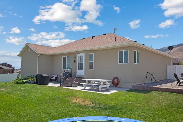 Rear exterior featuring a stucco finish, brown shingle roof, and multiple windows