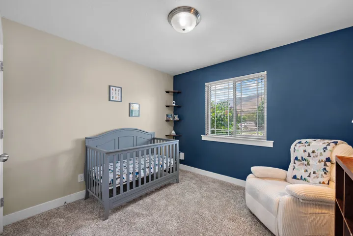 Carpeted room featuring a window with blinds, a contrasting accent wall, and built-in corner shelving