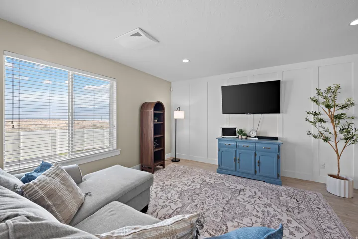 Spacious room featuring a large window, light-toned walls, and wood-finish flooring