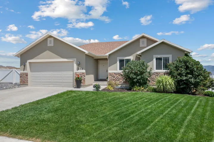 Contemporary single-story residence featuring a stucco and stone veneer exterior, an attached two-car garage, a concrete driveway, and a manicured lawn