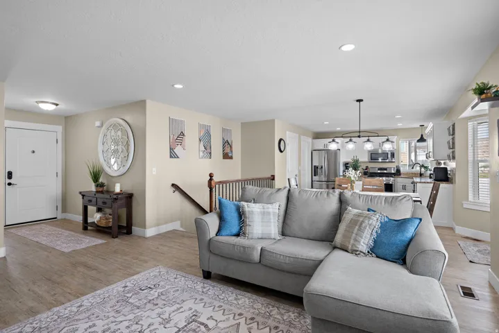 Open-concept living space featuring wood-finish flooring, recessed lighting, and a white entry door