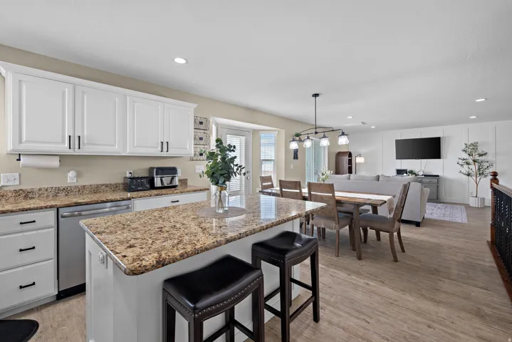 Open-concept kitchen featuring an island with stone countertops, white cabinetry, and stainless steel appliances