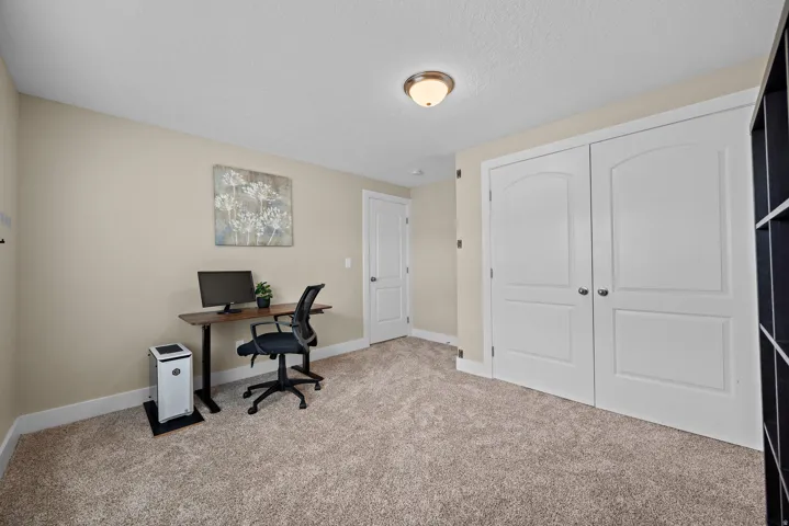 Neutral-toned room featuring a light beige carpet, white baseboards, and a semi-flush mount ceiling light fixture