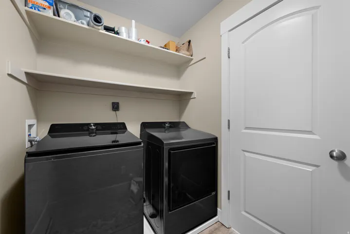 Laundry area featuring two wall-mounted shelves, neutral wall paint, and a white interior door with an arched panel detail