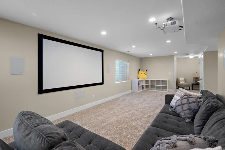 Media room featuring a wall-mounted projection screen, ceiling-mounted projector, and integrated wall speakers