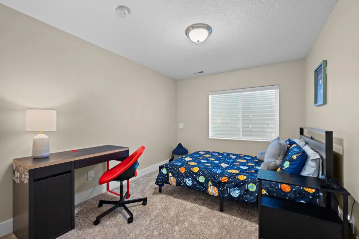 Interior room featuring neutral wall tones, textured carpeting, a window with blinds, and a semi-flush mount ceiling light fixture