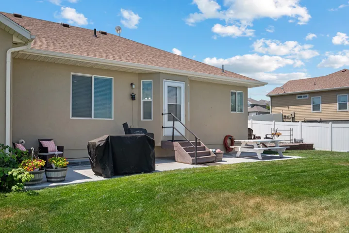Expansive backyard featuring a manicured lawn, a large concrete patio, and a privacy fence