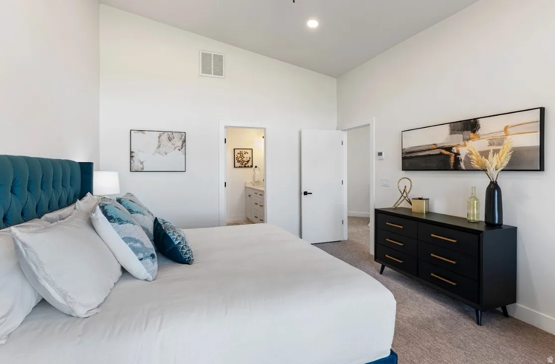 Vaulted ceilings define this carpeted room, featuring white walls and recessed lighting