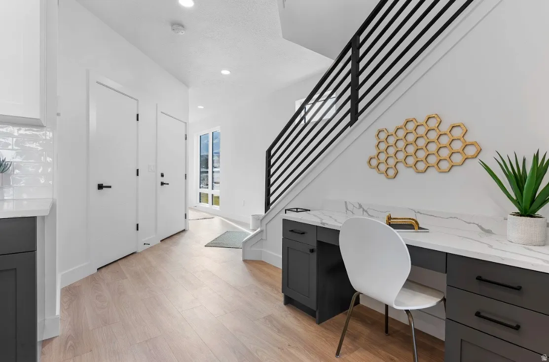 Integrated workspace featuring a white marble-look countertop and dark cabinetry with black hardware, complemented by light wood-finish flooring