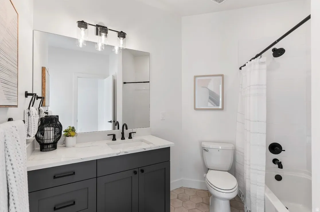 Bathroom featuring a vanity with dark cabinetry and a light countertop, a rectangular mirror, and a three-light fixture
