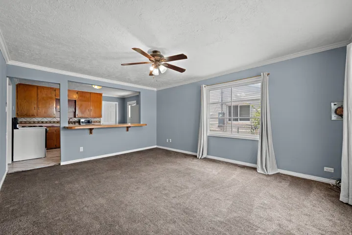 Living area with carpet flooring, light blue wall paint, and white crown molding