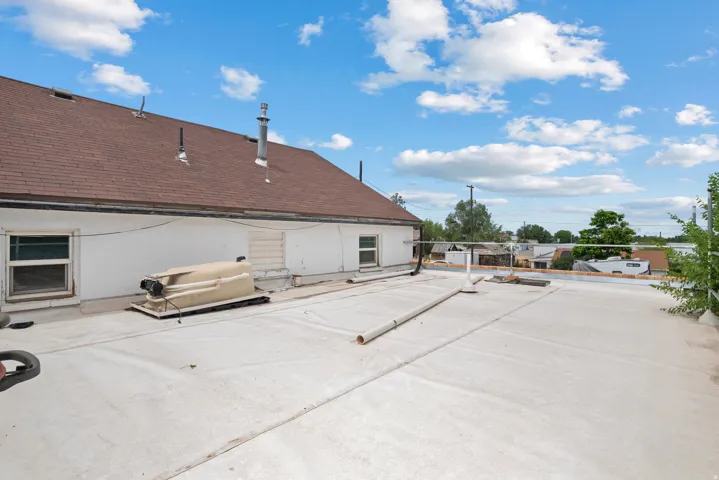 Expansive flat roof with a gravel-covered tar roof section and a brown shingle roofline
