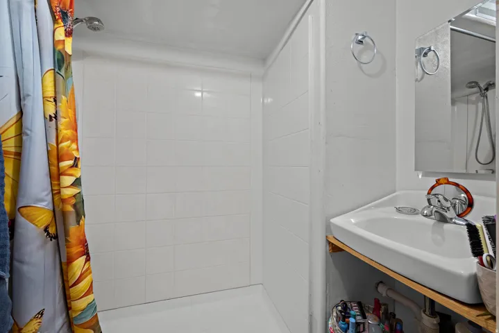 Shower stall with white ceramic tile surround and a matching white shower pan